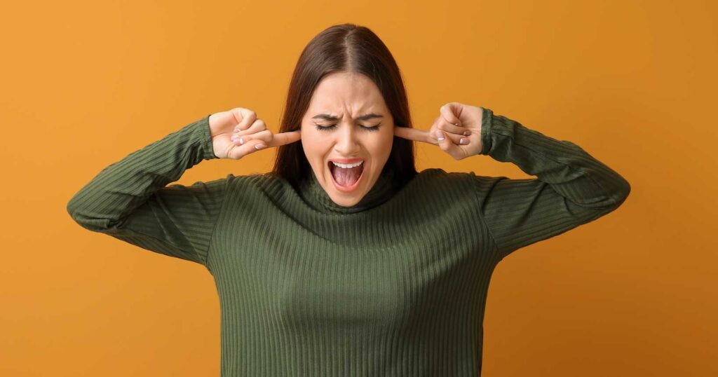 Bild: Frau erträgt den Lärm nicht und hält sich die Ohren zu